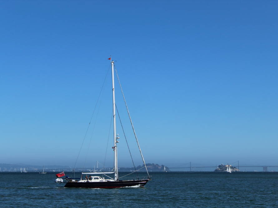 HERO image of a single sailboat moving across calm water with hills in the background, symbolising how SMEs navigate growth using McKinsey’s “Growth Triple Play” — purpose, creativity, and analytics — to build high growth, multi vertical companies.