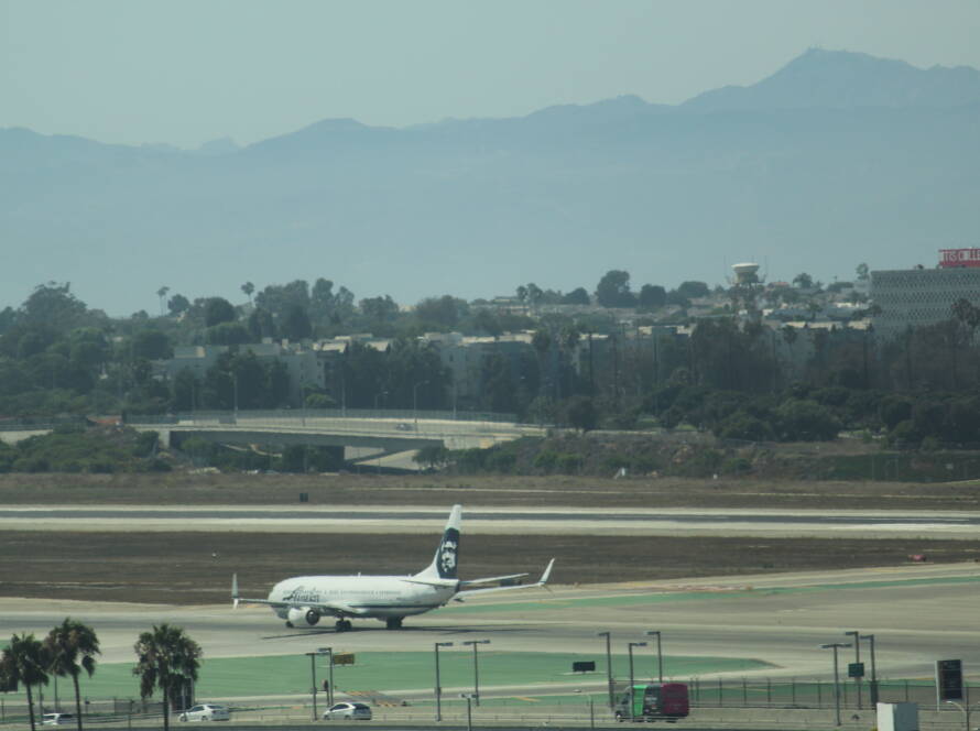 Alaska Airlines aircraft taxiing head on while surrounded by motorway traffic, symbolising Sarah Lomas’ precision health product evolution, financial discipline and strategic SME momentum in WK2.